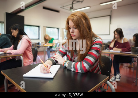 L'accent female student taking notes in class Banque D'Images