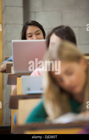 Jolie étudiante asiatique en utilisant son ordinateur portable dans une salle de conférences Banque D'Images