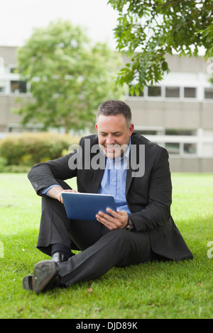 À l'aide de son maître heureux assis à l'extérieur du PC tablette sur le campus Banque D'Images