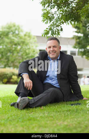 Conférencier heureux assis dehors sur le campus looking at camera Banque D'Images