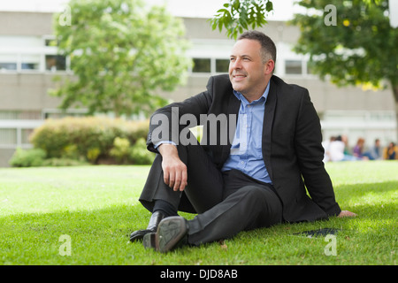 Conférencier heureux assis dehors sur le campus à la suite Banque D'Images
