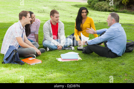 Les élèves heureux de discuter avec maître assis dehors sur le campus Banque D'Images