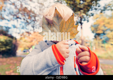 Allemagne, Bonn, Baby Boy covering face avec des feuilles d'automne je Banque D'Images