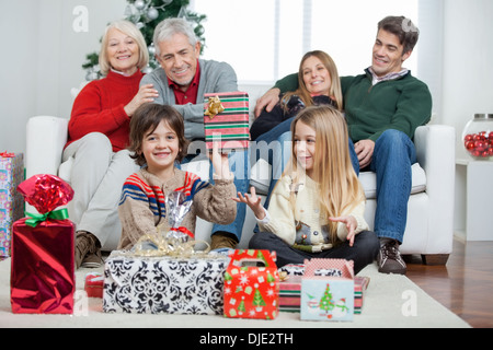 Boy Holding cadeau de Noël avec la famille dans la maison Banque D'Images