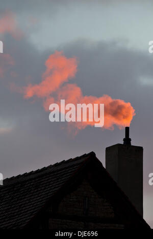 Wiesentheid, Allemagne. 26 nov., 2013. La fumée d'une cheminée est illuminée par le soleil du soir rouge à Wiesentheid, Allemagne, 26 novembre 2013. Photo : Daniel Karmann/dpa/Alamy Live News Banque D'Images