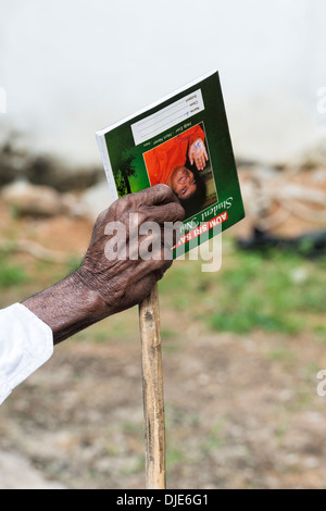 Old Indian mans hand holding bâton de marche et carnet de notes à Sri Sathya Sai Baba l'hôpital mobile. L'Andhra Pradesh, Inde Banque D'Images