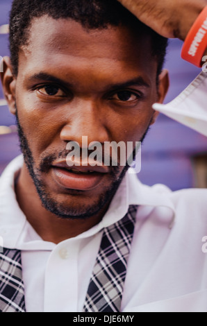 Afroamerican homme posant pour un tir contre une clôture en bois violet dans Deep Ellum. Dallas, Texas. Banque D'Images