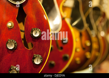 Un gros plan d'une guitare électrique rouge et ses divers contrôles tels que son volume. Il semble être utilisé et pour la vente dans un magasin Banque D'Images