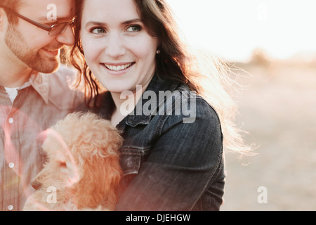 Un couple Holding leur chien de compagnie ; la plage Crescent, British Columbia, Canada Banque D'Images