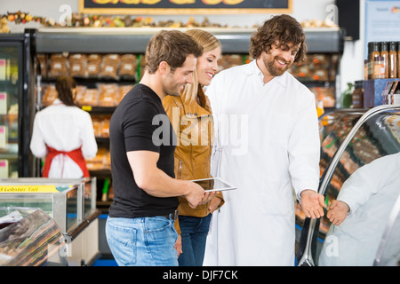 Vendeur aider dans l'achat de viande de couple Banque D'Images