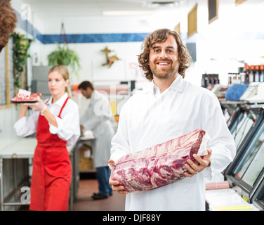 Portrait Of Happy Butcher Holding Paquet de viande Banque D'Images