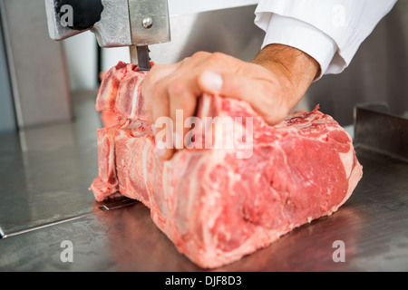 Scie à ruban à la main sur de la viande en tranches Banque D'Images