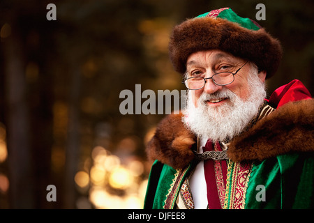 Portrait d'un Père Noël habillé en vert et rouge tresse pardessus et chapeau bordé de fourrure brun doux et un sourire Gentel Banque D'Images