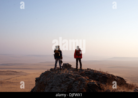 Deux randonneurs appréciant le lever du soleil du haut d'une montagne Banque D'Images