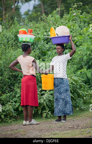 Les femmes avec lave-verres en équilibre sur leurs têtes et se serrent la main, salue l'île de Mfangano, Kenya Banque D'Images