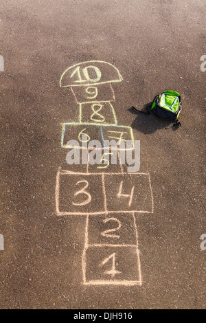 Jeu de marelle dessiné sur l'asphalte et sac à dos pour enfants à proximité de pose Banque D'Images