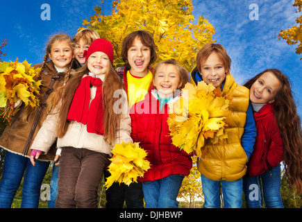 Groupe des sept enfants autour de 10 ans, garçons et filles, debout ensemble dans le parc avec Jaune automne érable on background Banque D'Images