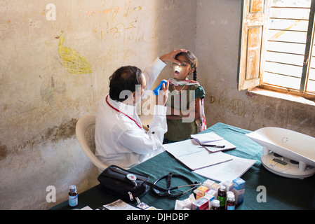 Médecin Pédiatrie indien l'examen d'une jeune fille à Sri Sathya Sai Baba mobiles de proximité hôpital clinique. L'Andhra Pradesh, Inde Banque D'Images