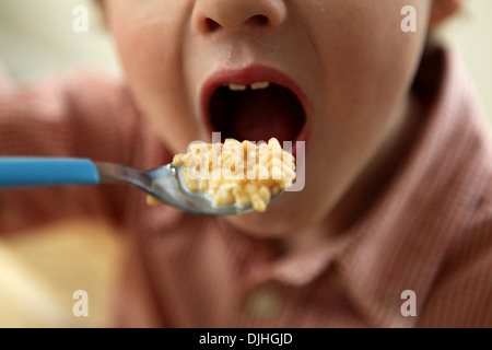 Close-up de bouche de l'enfant et la cuillère avec céréales petit déjeuner Banque D'Images