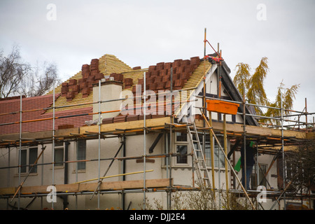 UK Workman debout sur un échafaudage travaille sur la réfection de la toiture d'une maison individuelle Banque D'Images