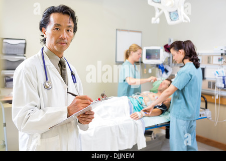 Doctor Holding Clipboard Examining patient avec les infirmières Banque D'Images