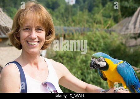 Femme en bleu et jaune de l'ara-sur son bras Banque D'Images