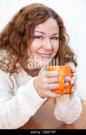 Cheerful attractive woman avec verre d'assise à la table, isolé sur fond blanc Banque D'Images