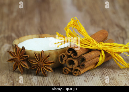 L'anis étoilé appuyé contre des bâtons de cannelle attaché avec du ruban jaune string à côté de sucrier en bois Banque D'Images