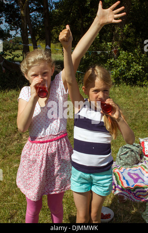 Deux filles boire squash, debout sur un pique-nique dans la campagne, les deux filles très soif à Somerset, Royaume-Uni. Banque D'Images