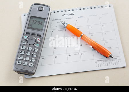 Téléphone sans fil combiné avec un stylo pointant vers le jour de l'An avec nouvelle lune sur un calendrier vide page pour janvier 2014 Banque D'Images