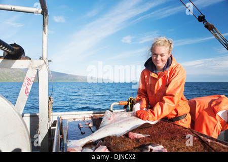 Jeune femme l'éviscération et la pêche commerciale au flétan près de False Pass In Morzhovoi Bay, sud-ouest de l'Alaska, l'été. Banque D'Images