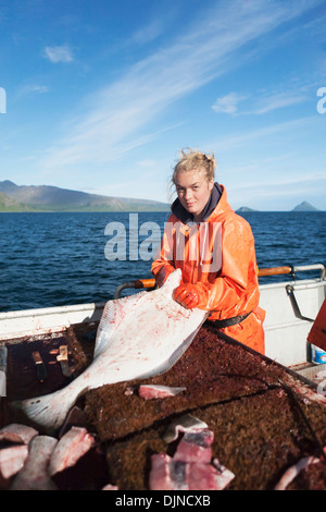 Jeune femme l'éviscération et la pêche commerciale au flétan près de False Pass In Morzhovoi Bay, sud-ouest de l'Alaska, l'été. Banque D'Images