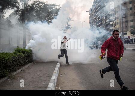 Le Caire, Égypte. 29 nov., 2013. Les protestataires s'enfuient de gaz lacrymogènes tirés par la police anti-émeute lors d'affrontements avec la police anti-émeute à l'extérieur de l'El-Qobba Palace, également connu sous le nom de Maison Présidentielle égyptienne, au Caire, Égypte, 29 novembre 2013. Les manifestants ont marché le vendredi à travers le pays pour s'opposer à la nouvelle loi de protestation publié dimanche dernier que les casseroles des manifestations sans avis préalable. Credit : Amru Salahuddien/Xinhua/Alamy Live News Banque D'Images