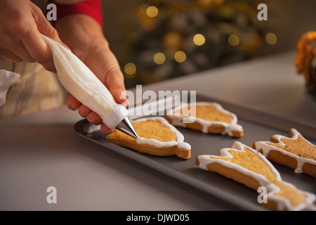 Gros plan sur les jeunes housewife decorating christmas cookies avec glacis Banque D'Images