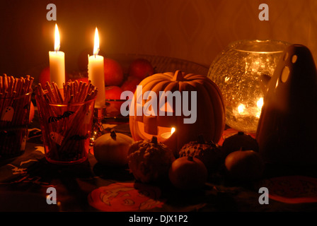 Set de table pour une fête d'Halloween avec des citrouilles, un fantôme, des bougies, des collations et des fruits. Banque D'Images