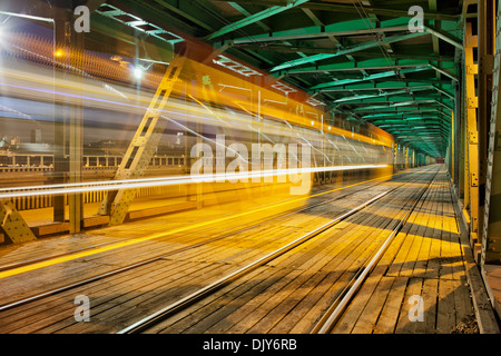 Résumé Le tram light trail dans la partie inférieure de la charpente en acier Gdanski Bridge à Varsovie, Pologne, vanishing point de vue. Banque D'Images