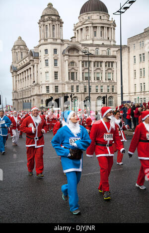 Coureurs de Noël à Liverpool, Merseyside, Royaume-Uni 1 décembre 2013. Les coureurs de la rue James à Liverpool Santa Dash à partir du Pier Head et essayer de briser le Guinness World Record pour le "plus grand rassemblement de Santa" qui se dresse à un incroyable 13 000 et qui tente également de monter à plus de 5 millions de livres sterling au total ces dernières années. Festive Fun Run soutient l'appel de Noël texte ITV cette année pour aider à recueillir des fonds pour Age UK, Anthony Nolan, Carers UK, Marie Curie Cancer Care, ensemble pour les courtes vies et Whizz-Kidz. Banque D'Images