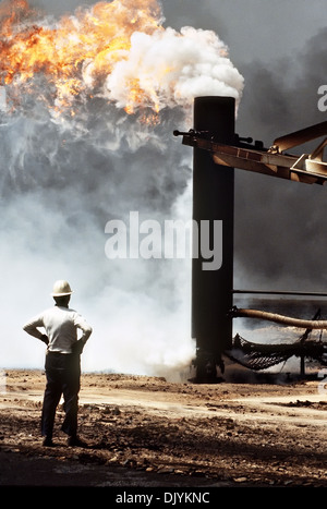 Les pompiers de l'huile et les foulques bottes de lutte contre l'utilisation de l'entreprise et une grue pour cap un puits de pétrole dans le sillage de l'opération Tempête du désert, le 7 avril 1991 dans les champs de pétrole, le Koweït Ahman. Le puits, situé dans l'Ahman des champs de pétrole, est l'un des nombreux incendiées par les forces iraquiennes avant leur retraite du Koweït. Banque D'Images
