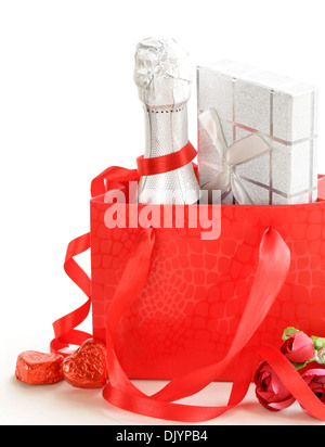 Bouteille de champagne de fête avec du chocolat et des cadeaux sur un fond blanc Banque D'Images