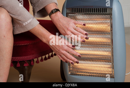 Femme au chaud par un feu électrique Banque D'Images