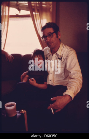 Ernest Watkins est photographié en train de se détendre avec son fils Kevin dans le salon de leur nouvelle maison. L'image capture un moment familial paisible dans leur vie nouvellement installée. Banque D'Images