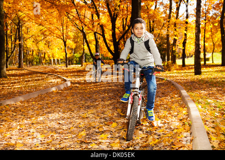 Heureux noir de 10 ans boy riding a bicycle en automne parc avec son petit frère Banque D'Images