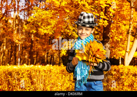 Happy 8 ans boy wearing hat and holding bouquet de feuilles d'oranger à l'érable Banque D'Images
