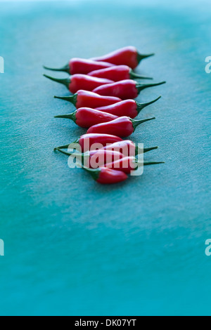 Chili Peppers, Capsicum, disposées sur une planche à découper en plastique vert Banque D'Images