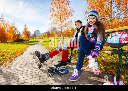10 et 11 ans couple d'enfants de l'école, un garçon girl putting sur rollers en automne chaud vêtements Banque D'Images