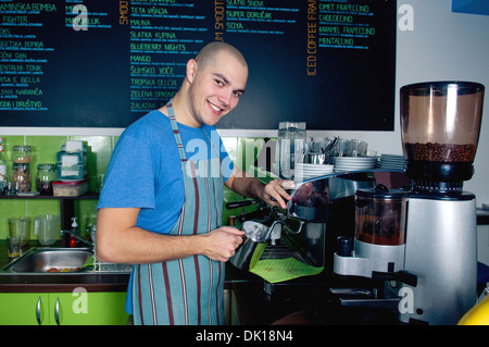 Jeune barman de sourire et de faire de tasse de café. Banque D'Images