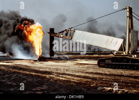 Les pompiers de l'huile et les foulques bottes de lutte contre l'utilisation de l'entreprise et une grue pour cap un puits de pétrole dans le sillage de l'opération Tempête du désert, le 7 avril 1991 dans les champs de pétrole, le Koweït Ahman. Le puits, situé dans l'Ahman des champs de pétrole, est l'un des nombreux incendiées par les forces iraquiennes avant leur retraite du Koweït. Banque D'Images