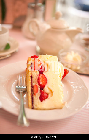 Close up portrait of tranche de gâteau au fromage aux fraises sur la plaque à côté de la théière Banque D'Images