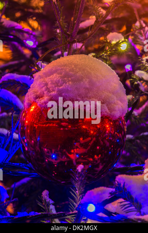 Joyeux Noël. Big Red Boule décorative sur un arbre de Noël à l'air libre. Une tasse de neige sur le haut de la balle Banque D'Images