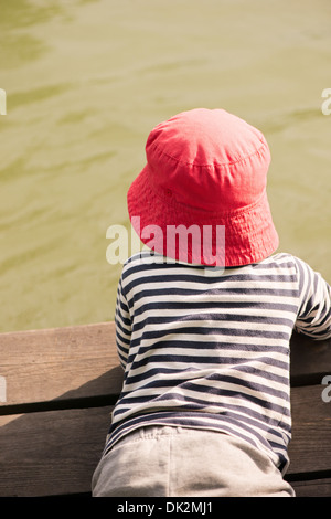 Little girl lying on Jetty, regardant l'eau Banque D'Images